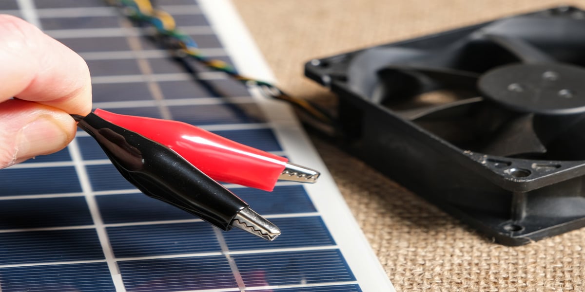 DIY Solar Power Systems: Are They Worth It? Expert Electric shows alligator clips wiring a DIY solar power system with cooling fan.