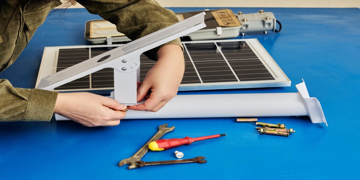 DIY Solar Power Systems: Are They Worth It? Expert Electric shows DIY solar power system bracket assembly with tools on blue workbench.