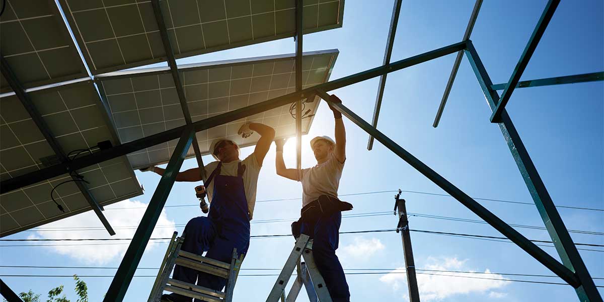 Workers installing solar panels at sunrise. Expert Electric is debunking myths about solar energy, showing how solar power works efficiently in various climates.