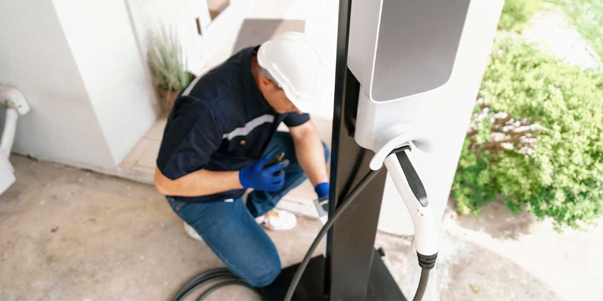 Certified electrician installing a home EV charger, reinforcing the message of Electric Vehicle Myths Debunked by showcasing how simple, fast, and professional EV home charging setups can be with expert help.