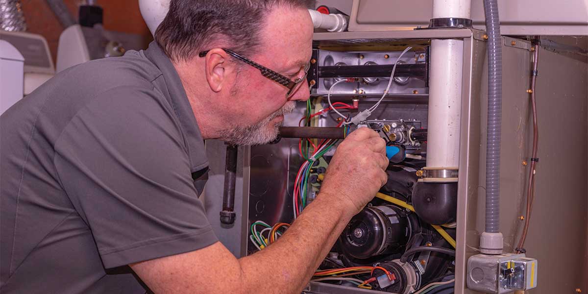 Heating system got you down? Expert Electric provides expert furnace repair and maintenance services. This image highlights a skilled technician inspecting and repairing a furnace unit, addressing wiring and mechanical components to ensure your heating system operates efficiently. Trust Expert Electric for reliable solutions to keep your home warm and safe.