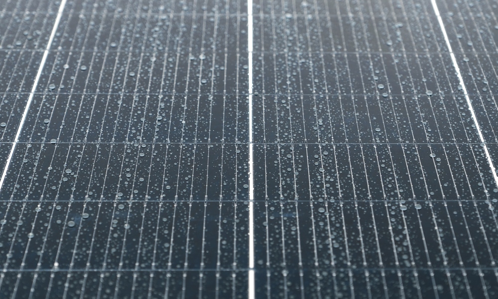 Close-up macro view of solar panel surface with raindrops on the glass cells, symbolizing clean energy and nature.