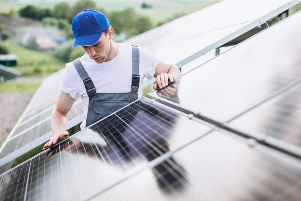 Man worker in the field by the solar panels