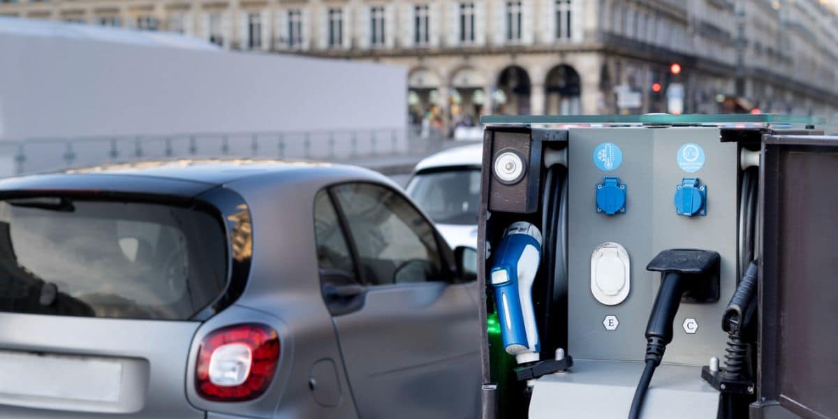 Understanding EV Charging Stations: Types, Locations, and Costs shown with a compact EV using a street-side charger in a busy city—powered by Expert Electric.