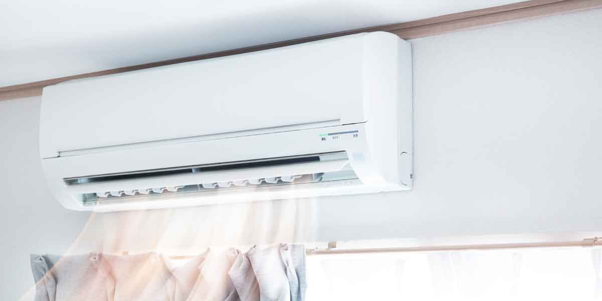 Mini split mounted above window pushing out air.