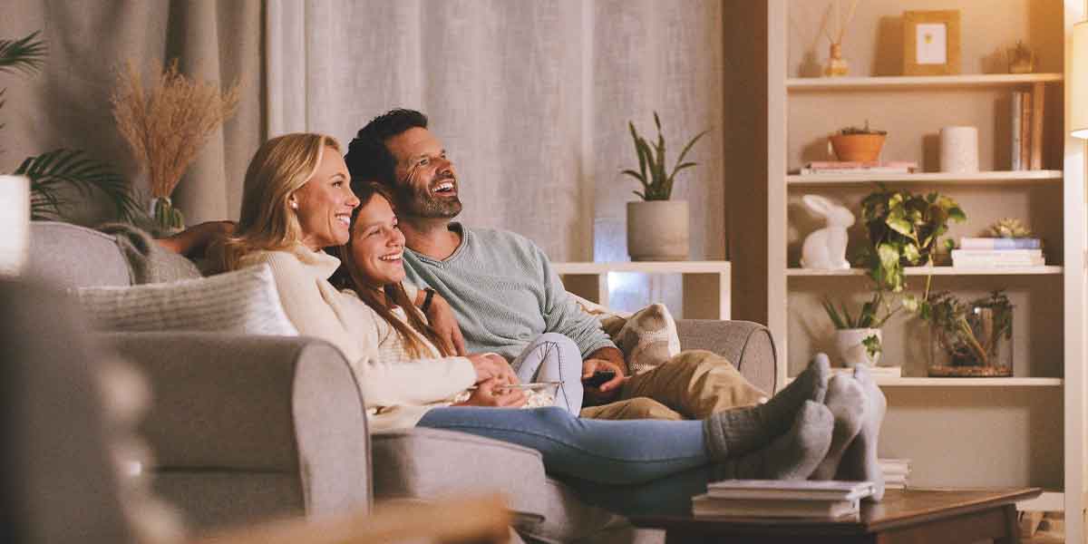 Happy Family of a Mother, Father and Daughter sitting on a couch together, enjoying an evening.