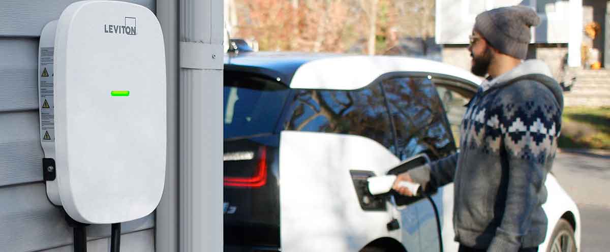 Man plugging in a Leviton EV charger to his car.